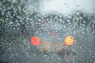 Spot focus  Drops of rain flowing into the car glass At the time of rain Blurred background as a car taillight.