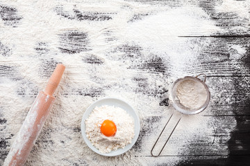 flour and ingredients on black table. Top view