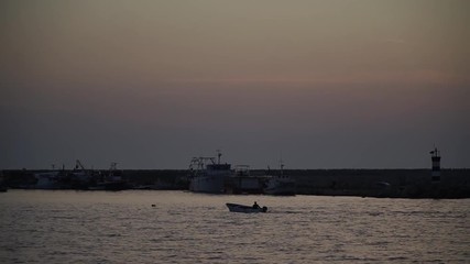 the silhouette of the boat is floating at sunset on the sea by the lighthouse
