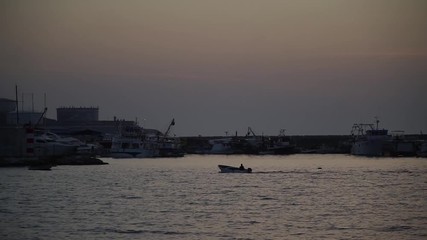 the silhouette of the boat is floating at sunset on the sea by the lighthouse