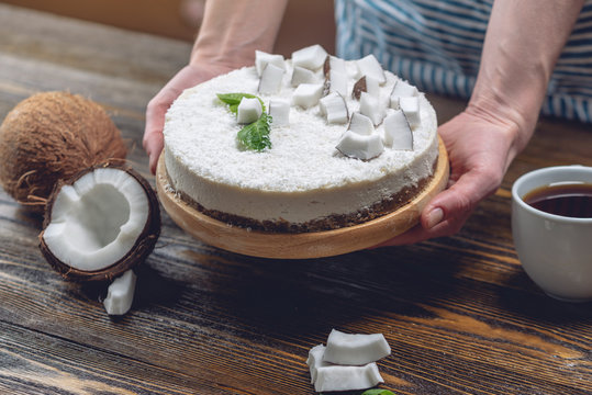 Confectioner decorates coconut raw cake with white pulp and mint. Healthy vegan dessert. Gluten and sugar free food