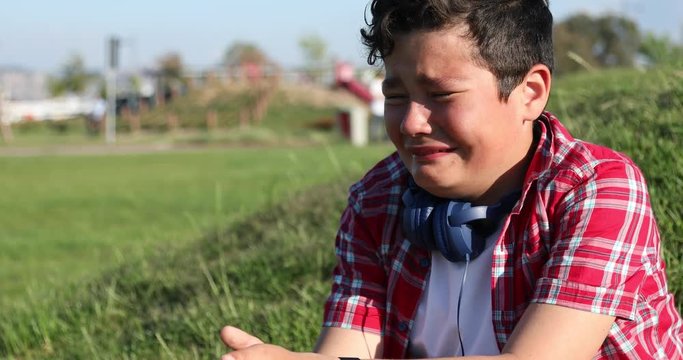 Cute caucasian preteen boy crying in the park