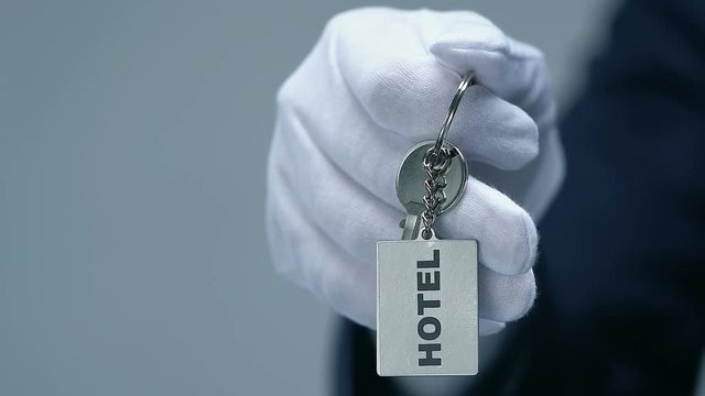 Hotel word on keychain in male doorman hand, friendly luxury resort service
