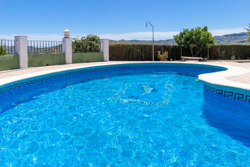 A beautiful luxury swimming pool at a villa in the holiday destination of Malaga in Spain under blue sky in summer