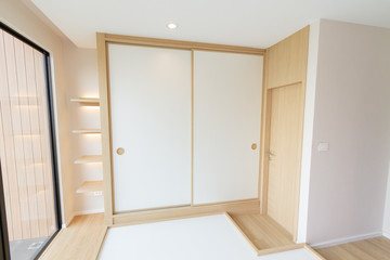 Large wardrobe Japanese-style white sliding door with a light brown wood paneling In the modern...
