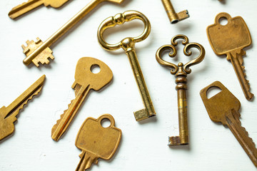Lot of keys old and new yellow gold color on a white background