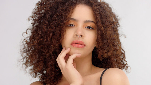 hair blowing closeup portrait of mixed race model with freckles touches her skin