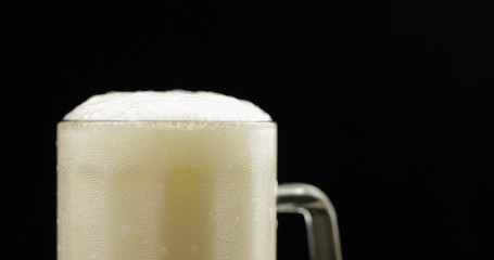 Cold Light Beer in a glass. Craft Beer foam close-up. Black background
