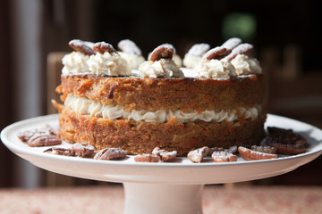freshly baked Carrot Cake with whipped cream and walnuts on a cake stand