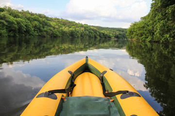 Yellow boat nose  on the still waters of the Danube River.  Mountains and forests frame the background