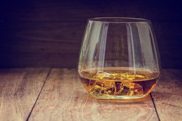 glass of whiskey with ice on a wooden background
