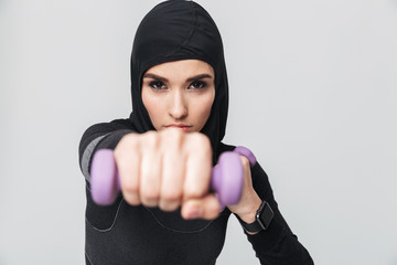 Muslim fighter boxer posing isolated over white wall background make exercises with dumbbells.
