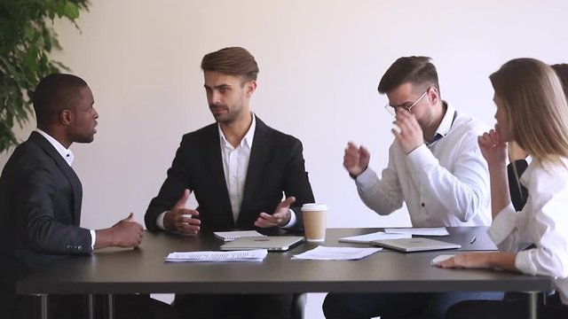 Angry african businessman disagree with caucasian colleague fight at meeting