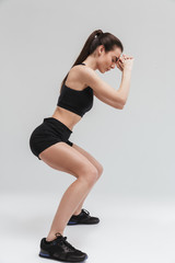 Naklejka premium Beautiful young sport fitness woman make exercises isolated over grey wall background.