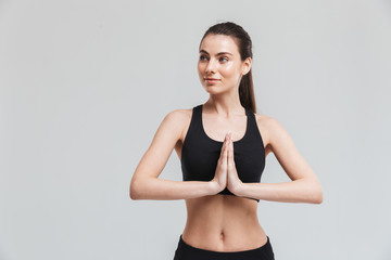 Fototapeta premium Beautiful young sport fitness woman make exercises isolated over grey wall background.