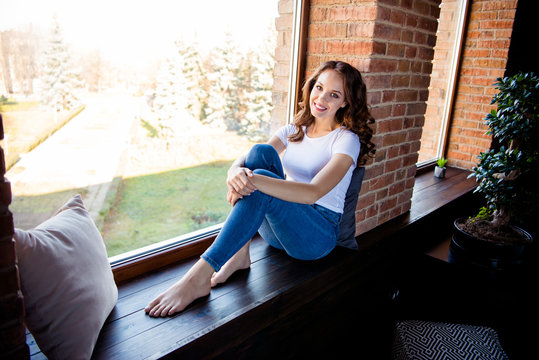 Portrait of her she nice-looking attractive lovely charming fit slim thin cheerful cheery wavy-haired girl sitting on window sill at industrial loft wooden brick style interior indoors