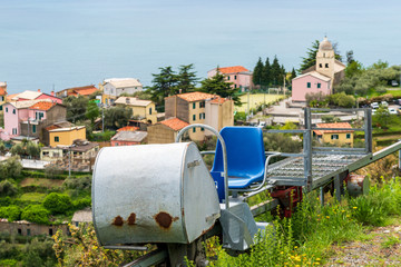 Fototapeta na wymiar The trenino, a monorail train used to transport tools, grapes and olives, in Cinque Terre, Italy, with the colorful houses of Volastra village and Ligurian Sea in the background.