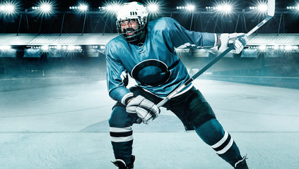 Fototapeta na wymiar Ice Hockey player athlete in the helmet and gloves on stadium with stick. Action shot. Sport concept.