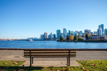 View from bench with Landmark of Vancouver, British Columbia background. View from Stanley Park and seawall in Vancouver, Canada. It is largest urban park with beaches, trails, scenic seawall