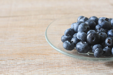 Blueberry in glass plate on wooden background.