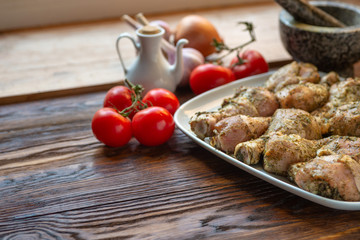 Raw chicken legs with herbs and spices on white dish.