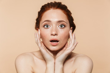 Shocked young redhead woman posing isolated over beige wall background.