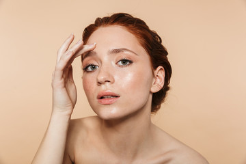 Pretty young redhead woman posing isolated over beige wall background looking at camera as a mirror.
