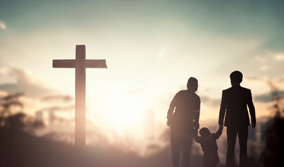 Family worship and praise concept: family praying before the cross © paul