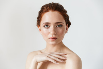 Young redhead woman posing isolated over white wall background.