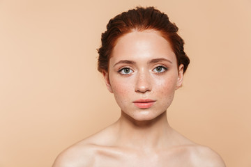 Amazing young redhead woman posing isolated over beige wall background.