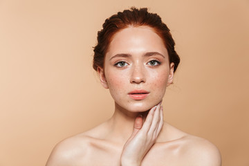 Amazing young redhead woman posing isolated over beige wall background.