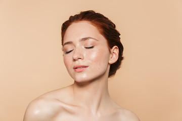 Amazing young redhead woman posing isolated over beige wall background.