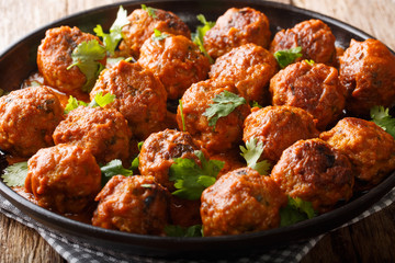 Asian chicken meatballs in a creamy coconut sauce with red curry closeup on a plate. horizontal