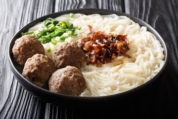 Indonesian traditional food bakso meatballs with noodles, onions, greens and broth close-up on a plate. horizontal