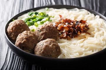 Delicious bakso meatballs with noodles, caramelized onions, greens and broth close-up on a plate. horizontal