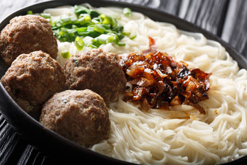 Bakso meatballs with noodles, fried onions, greens and broth close-up on a plate. horizontal