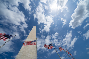 American flags blowing in the wind with the Washington Monument along the National Mall. Partly...
