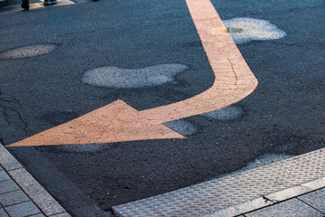 Yellow arrow traffic sign on an asphalt road.