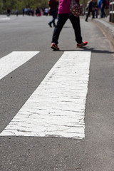 Lady crossing an asphalt road on a white crossing line near a tourist spot in Japan.