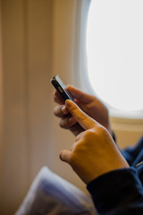 Girl teenager's hands using a smartphone on the airplane while waiting for taking off during morning time.