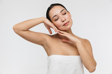 Portrait of attractive half naked asian woman touching her clear skin and looking aside