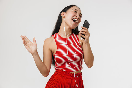 Image of young asian woman wearing casual clothes listening to music on cellphone and singing