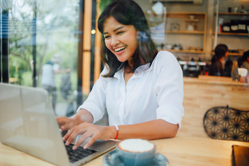 Asian woman using laptop computer in coffee shop cafe