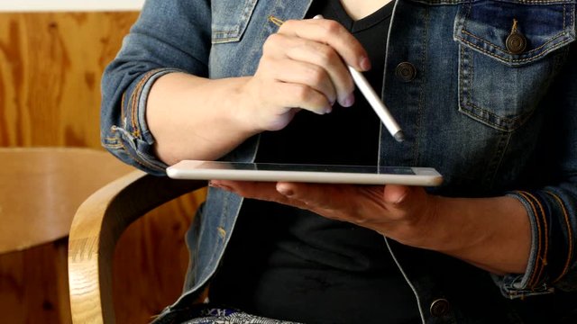 Woman using digital tablet with drawing pencil at cafe