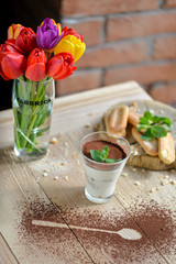 Tiramisu dessert in a glass on a table with flowers in the decor