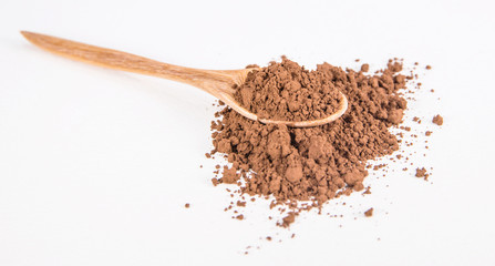 cocoa powder and wooden spoon on white