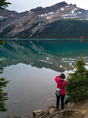 Tourist photographing at lakeside, Bow lake, Improvement District 9, Banff National Park, Alberta, Canada