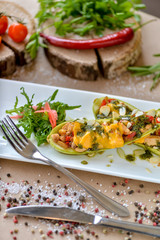 baked zucchini with cheese and vegetables on a rectangular plate