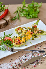 baked zucchini with cheese and vegetables on a rectangular plate