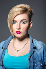 Young woman with short trendy haircut and bright eyeliner makeup over grey background